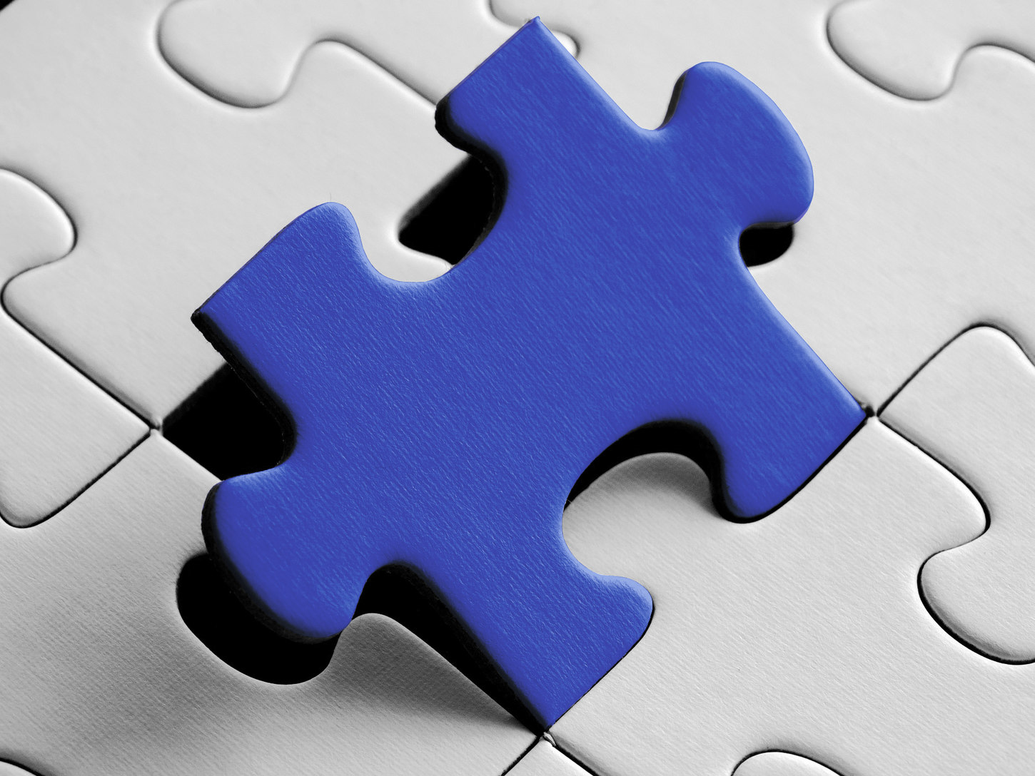 Puzzleteile, eines davon in blauer Farbe hervorgehoben